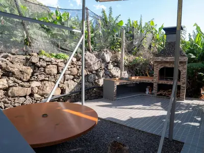 a patio with a table and a stone fireplace at Casa dos Anjos in Ponta do Sol
