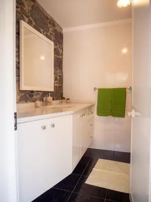 a bathroom with white cabinets and a green towel at Casa dos Anjos in Ponta do Sol