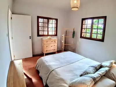a bedroom with a bed and a dresser and two windows at Beach Tree House in Porto Santo