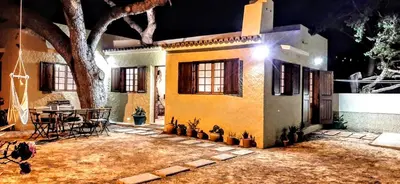 a house with a table and a tree in the yard at Beach Tree House in Porto Santo