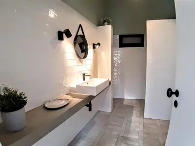 a white bathroom with a sink and a mirror at Beach Tree House in Porto Santo