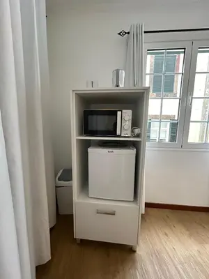a white shelf with a microwave on top of it at Palmar Rooms in Funchal