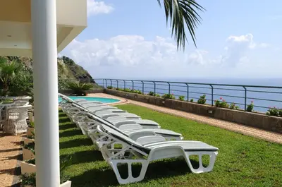 a row of chaise lounge chairs overlooking the ocean at Vivenda Belo Horizonte in Caniço