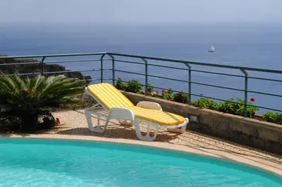 a yellow chair sitting next to a swimming pool at Vivenda Belo Horizonte in Caniço