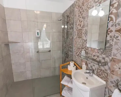 a small bathroom with a sink and a mirror at Vitorina Corte Guesthouse in Funchal