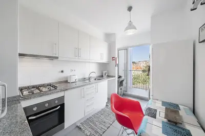 a white kitchen with a red chair and a glass table at Rooftop Funchal - By Wehost in Funchal