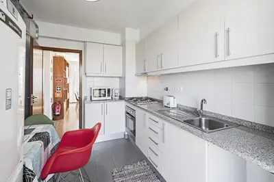 a white kitchen with a sink and a red chair at Rooftop Funchal - By Wehost in Funchal