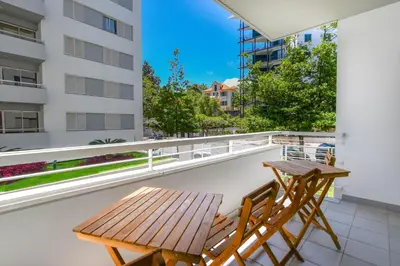 a balcony with two tables and chairs on a building at Apartamento Costa Do Sol in Funchal