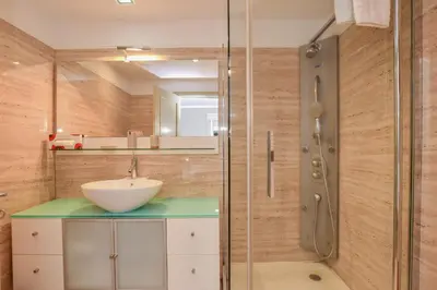 a bathroom with a sink and a glass shower at Apartamento Costa Do Sol in Funchal