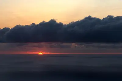 a sunset over the ocean with the sun hiding behind clouds at Recanto das Florenças (1) in Arco da Calheta