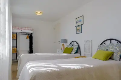 two beds in a room with white walls and green pillows at Recanto das Florenças (1) in Arco da Calheta