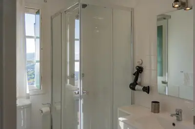 a bathroom with a shower with a sink and a mirror at Recanto das Florenças (1) in Arco da Calheta