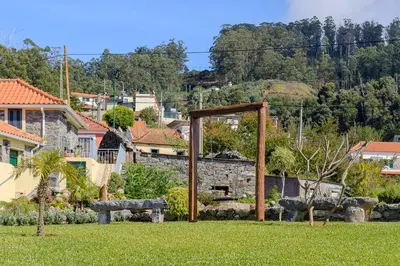 a garden with a wooden arch in the grass at Recanto das Florenças (1) in Arco da Calheta
