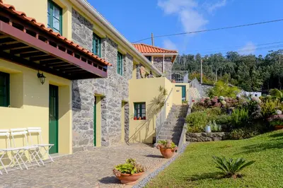 a stone house with a garden and a patio at Recanto das Florenças (1) in Arco da Calheta