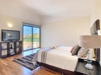 a bedroom with a bed and a tv and a window at Villa Moniz by LovelyStay in Funchal