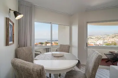 a white dining room with a white table and chairs at Alegria I by An Island Apart in Funchal