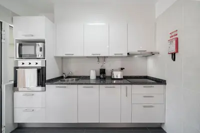 a white kitchen with white cabinets and a sink at Alegria I by An Island Apart in Funchal