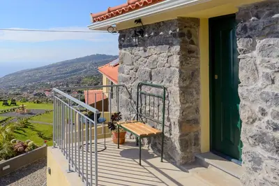 a balcony of a house with a wooden bench at Recanto das Florenças (2) in Arco da Calheta