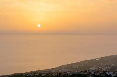 a sunset over a city with the sun in the sky at Recanto das Florenças (2) in Arco da Calheta