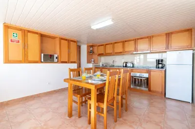a kitchen with a table and chairs and a refrigerator at Casa Raivinha in Arco da Calheta