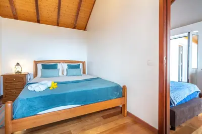 a bedroom with a bed with blue sheets and a mirror at Casa Raivinha in Arco da Calheta