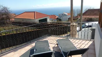 a balcony with two chairs and a view of the ocean at Casa Raivinha in Arco da Calheta