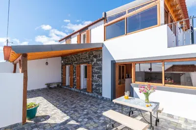 a house with a patio with a table and benches at Casa Raivinha in Arco da Calheta