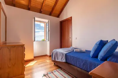 a bedroom with a blue bed and a window at Casa Raivinha in Arco da Calheta