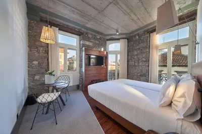 a bedroom with a large white bed and a table at Hotel Cajú in Funchal