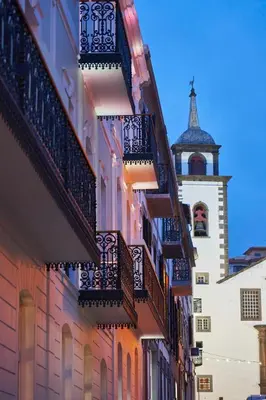 a building with balconies and a clock tower at Hotel Cajú in Funchal