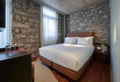 a bedroom with a large bed and a stone wall at Hotel Cajú in Funchal