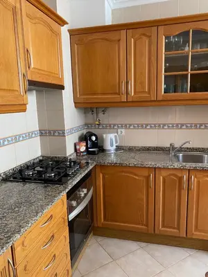 a kitchen with wooden cabinets and a stove top oven at Cozy Apartment in Porto Santo