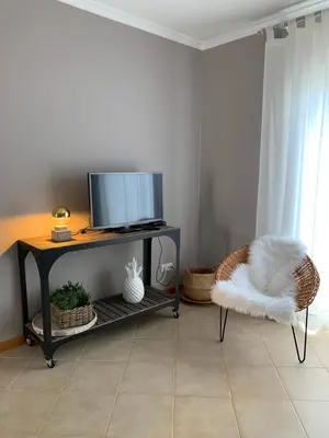 a living room with a tv and a chair at Cozy Apartment in Porto Santo