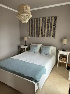 a bedroom with a large white bed with blue pillows at Cozy Apartment in Porto Santo