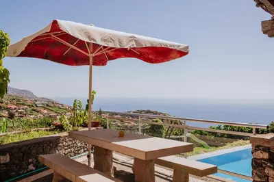 a picnic table with an umbrella next to a pool at Villa Sol by Amazing Madeira in Ponta do Sol