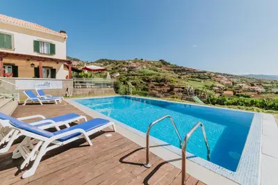 a swimming pool with two chairs and a house at Villa Sol by Amazing Madeira in Ponta do Sol