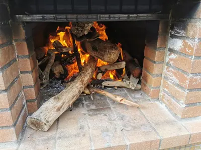 a brick fireplace filled with fire and logs at Casa Atlantico Dachterrassengeschoss in Ribeira Brava