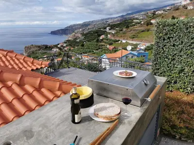 a grill with two plates of food and a glass of wine at Casa Atlantico tropischer Seitenflügel in Ribeira Brava