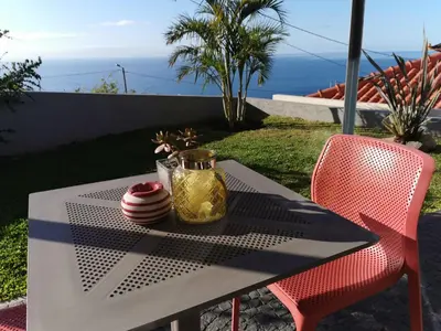 a table with a red chair and a glass jar on it at Casa Atlantico tropischer Seitenflügel in Ribeira Brava