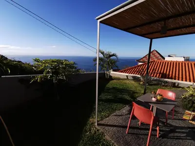 a patio with a table and chairs and the ocean at Casa Atlantico tropischer Seitenflügel in Ribeira Brava