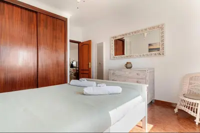 a bedroom with a large bed with a mirror on the wall at Apartment Praia Arrifana with BALCONY and SEA VIEW in Aljezur