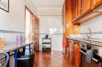 a kitchen with wooden cabinets and a counter top at Apartment Praia Arrifana with BALCONY and SEA VIEW in Aljezur