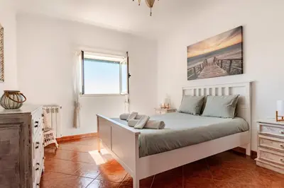 a white bedroom with a bed and a window at Apartment Praia Arrifana with BALCONY and SEA VIEW in Aljezur