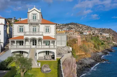 a large white house on a cliff next to the water at Luxury Barreirinha House old town by Holiday Rental Madeira in Funchal