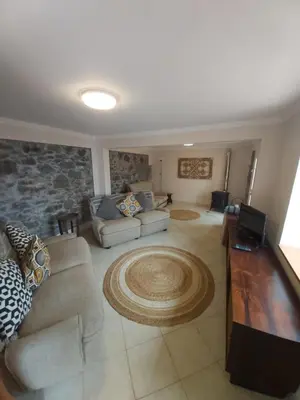 a living room with two couches and a stone wall at Banda Do Sol Self Catering Cottages in Estreito da Calheta