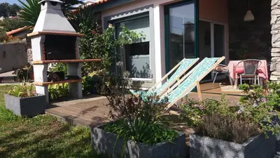 a porch with a couple of lounge chairs in front of a house at Banda Do Sol Self Catering Cottages in Estreito da Calheta