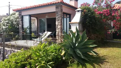 a small house with a chair and some plants at Banda Do Sol Self Catering Cottages in Estreito da Calheta