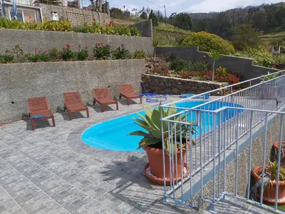 a patio with a pool and chairs and plants at Banda Do Sol Self Catering Cottages in Estreito da Calheta