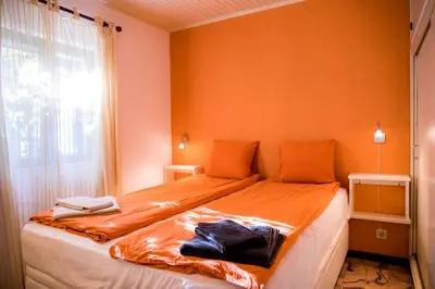a bedroom with a bed with orange walls and a window at Casa da Montanha in Luz