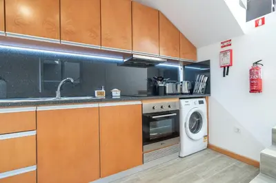 a kitchen with wooden cabinets and a washer and dryer at Casa Leonardo in Arco da Calheta